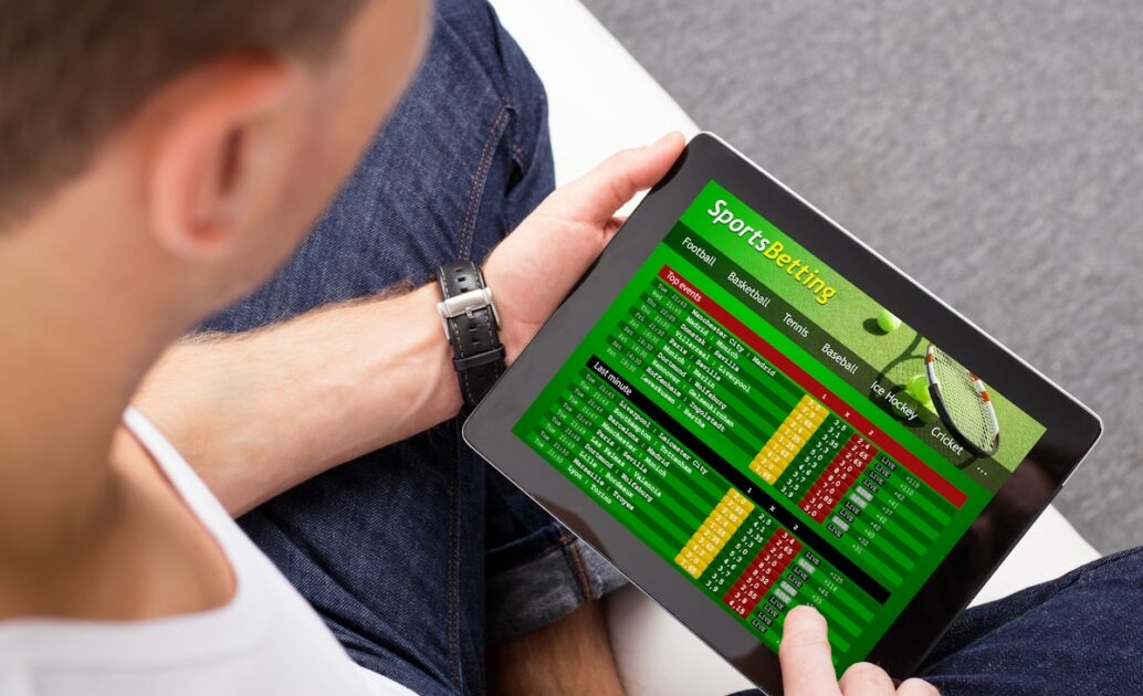 Man betting on sports using a betting app on a tablet